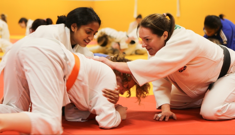 two young female judoka being coached